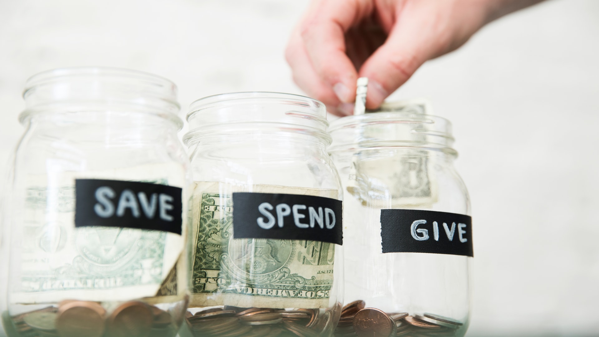 3 Jars labeled Save, Spend, and Give with money in them. Learn how to fill all three at Brookwood Church